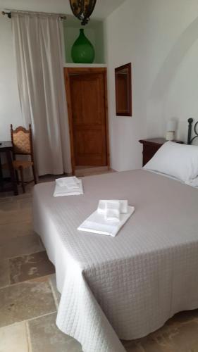 a white bed with two white towels on top of it at Masseria Parco di Castro in Montalbano