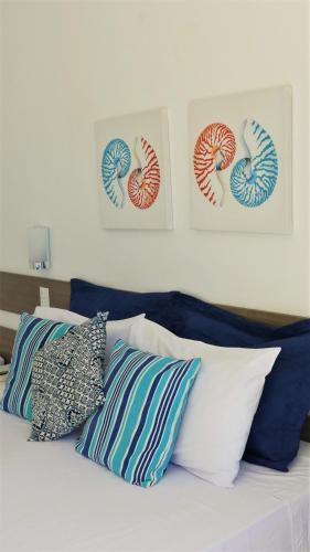 a bed with pillows on it with three pictures on the wall at Estrela Azul Guest House Búzios in Búzios