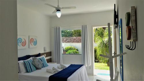 a white bedroom with a bed and a window at Estrela Azul Guest House Búzios in Búzios