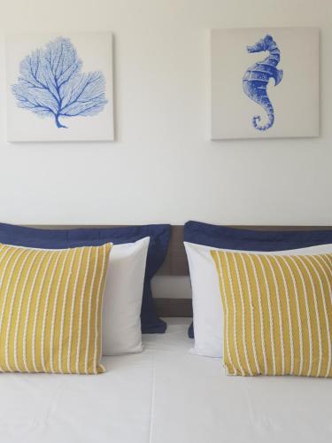 a bed with two pillows and two paintings on the wall at Estrela Azul Guest House Búzios in Búzios