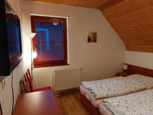 a bedroom with two beds and a table and a window at Chata Salma Jeseníky in Dolní Moravice