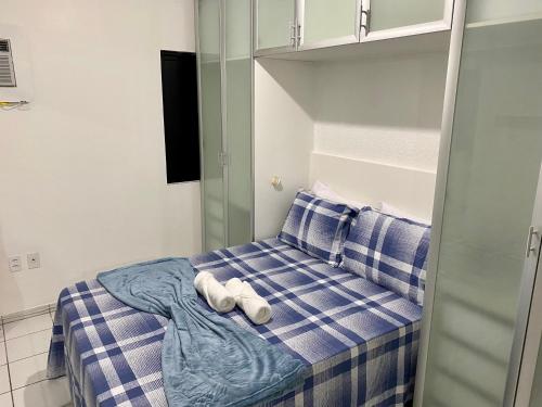 1 cama con manta de cuadros azul y blanco y 2 zapatos blancos en Perto da Praia e Piscina na cobertura, en Maceió