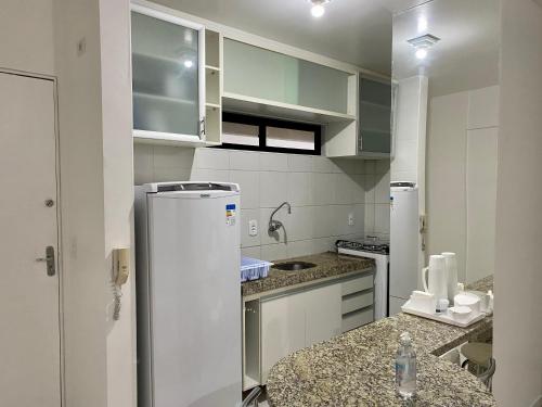 Una cocina con gabinetes blancos y un refrigerador. en Perto da Praia e Piscina na cobertura, en Maceió