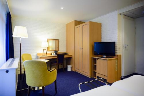a hotel room with a bed and a desk with a television at Fletcher Hotel Restaurant De Wipselberg-Veluwe in Beekbergen