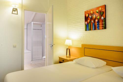 a bedroom with a bed and a painting on the wall at Fletcher Hotel Restaurant De Wipselberg-Veluwe in Beekbergen