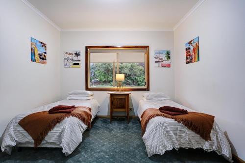 two beds in a room with a window at Farm Stay & Iconic Water Views - 32 Zachary Drive in Mallacoota