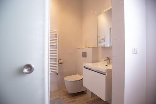 a white bathroom with a toilet and a sink at Alessia Apartment in the Old Town in Timişoara