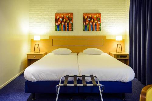a bedroom with a large white bed with two chairs at Fletcher Hotel Restaurant De Wipselberg-Veluwe in Beekbergen