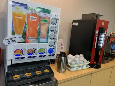 a counter with a drink dispenser next to a refrigerator at AZ Inn Obu in Obu