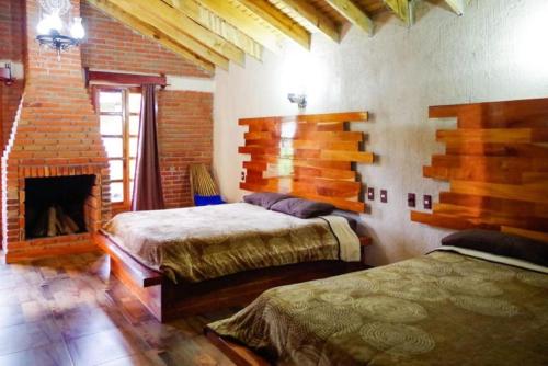 a bedroom with two beds and a fireplace at Cabañas del Bosque in San Miguel Regla