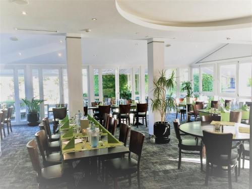 a dining room with tables and chairs and windows at Hotel Ambiente Walldorf in Walldorf
