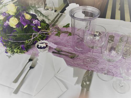 a table with wine glasses and a bouquet of flowers at Hotel Ambiente Walldorf in Walldorf