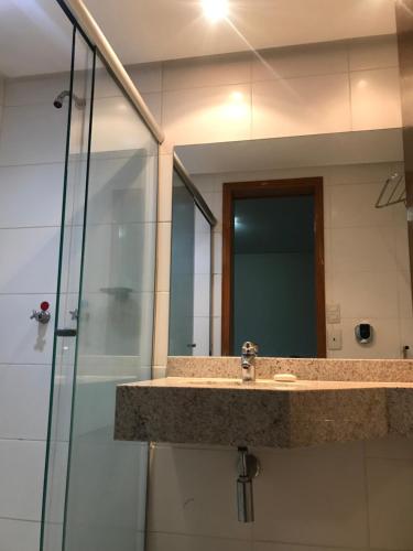 a bathroom with a sink and a shower with a mirror at Crystal Place in Goiânia