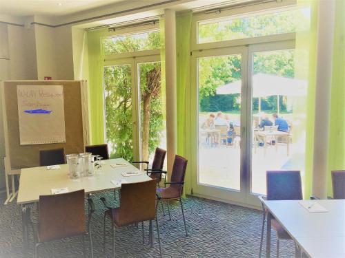 a conference room with tables and chairs and sliding glass doors at Hotel Ambiente Walldorf in Walldorf