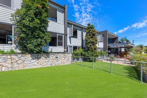 an apartment building with a stone wall and green grass at Altitude On Montville in Montville
