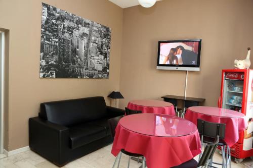 a living room with two tables and a couch and a tv at Hotel Bicocca in Milan