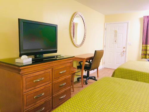 a bedroom with a television on a dresser with a desk at Classic Suites - Cleveland in Cleveland