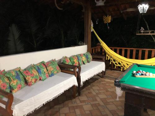 a porch with couches and a hammock and a table at Casa para temporada em Paraty RJ - Sítio Primavera in Paraty