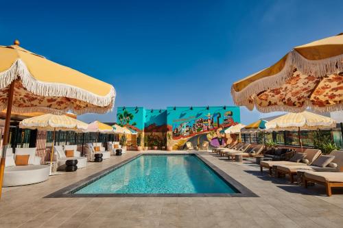 - une piscine dans un complexe avec des chaises et des parasols dans l'établissement tommie Hollywood, part of Jdv by Hyatt, à Los Angeles