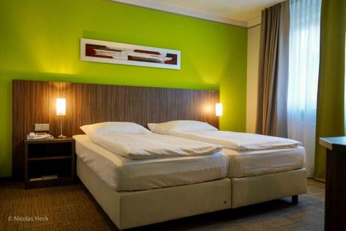 two beds in a room with a green wall at Hotel Ambiente Walldorf in Walldorf