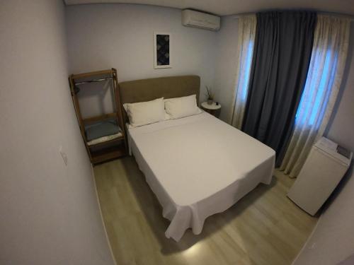 a bedroom with a large white bed and a mirror at Hotel e Pousada Magic in Penha