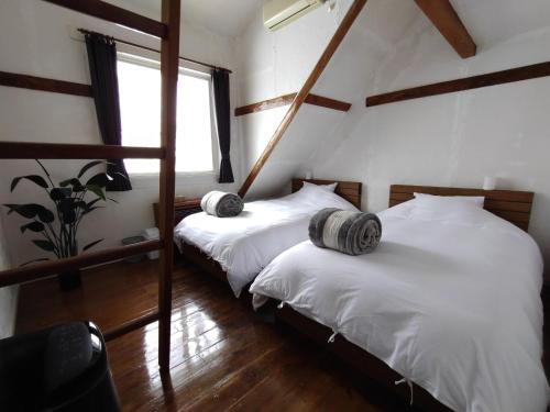 two twin beds in a room with a window at Keimichi Guest House in Hakuba