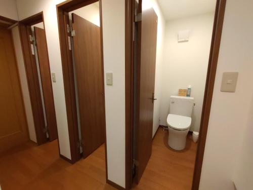 a bathroom with a toilet and a wooden door at Keimichi Guest House in Hakuba