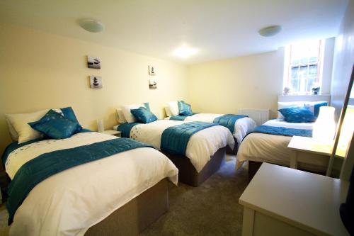 a room with three beds with blue pillows at Heritage City - Central New Town Apartment in Edinburgh