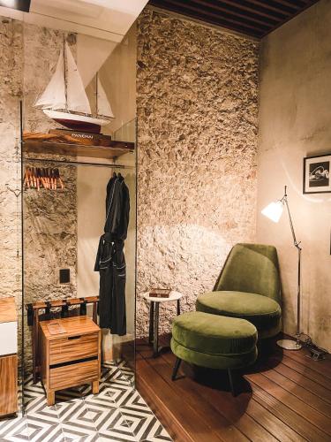 a living room with a green chair and a stool at Diez Diez Collection in Mérida