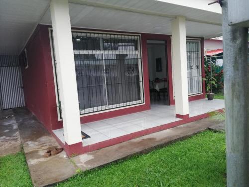 une terrasse couverte à l'avant d'une maison avec une porte rouge dans l'établissement Morpho Casa Vacacional, à Fortuna