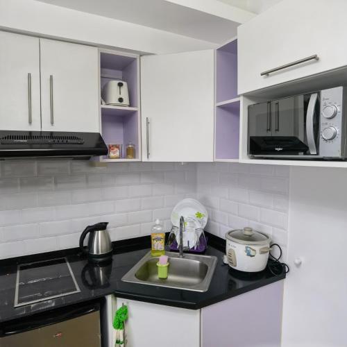 a kitchen with white cabinets and a sink at Avida Davao by davaobnb & Lemonique Homes in Davao City