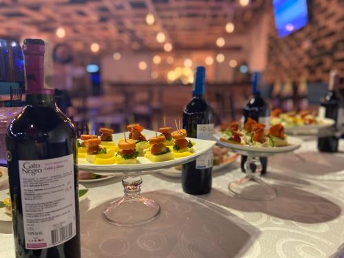 a table with two plates of food and bottles of wine at Hotel Las Palmeras Gachancipa in Gachancipá