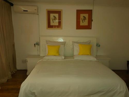 a large white bed with yellow pillows in a room at Kea bed and breakfast in Mogwase