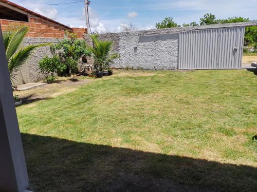 a yard with grass and a stone wall and a building at casa para alugar em Prado bahia. in Prado