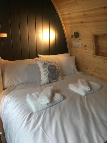 a bed in a wooden room with towels on it at Owls Retreat Glamping Pod with Hot tub in Keith