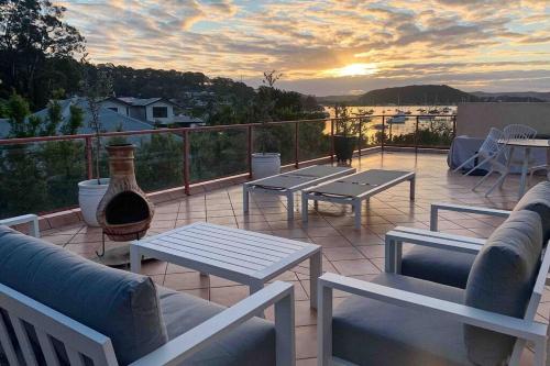 a patio with couches and tables and a sunset at Casa Parker Stunning 3bdrm apartment in Killcare in Killcare