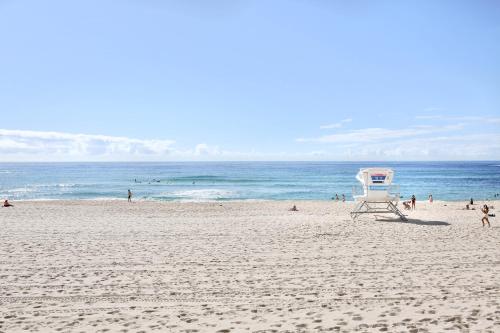 a lifeguard chair on a beach with people in the water at Miss Baker's Boutique Accommodation Bondi in Sydney