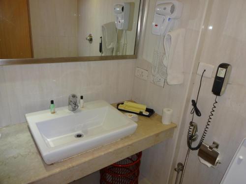 a bathroom with a sink and a phone on the wall at Savera Hotel in Chennai