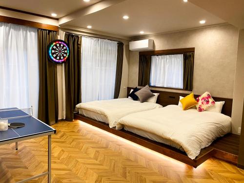 a bedroom with two beds and a table and windows at TABISAI HOTEL Suite 博多 in Fukuoka