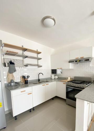 a kitchen with white cabinets and a black stove at OASIS Punta Cana Apartment in Punta Cana