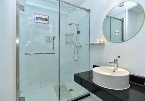 a bathroom with a glass shower and a sink at 银座精宿(黄岛金沙滩香江路商业街店) in Qingdao