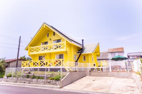 a yellow house with a fence in front of it at Awaji Large Log house in Goshiki 2 in Sumoto