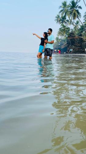 two people standing in the water on the beach at Tent by the bay, Alibaug Beach Camping, Revdanda in Alibaug