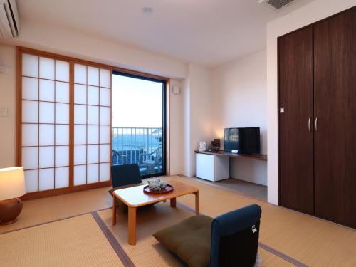 a living room with a table and a chair and a room at Izu Kansya in Atami