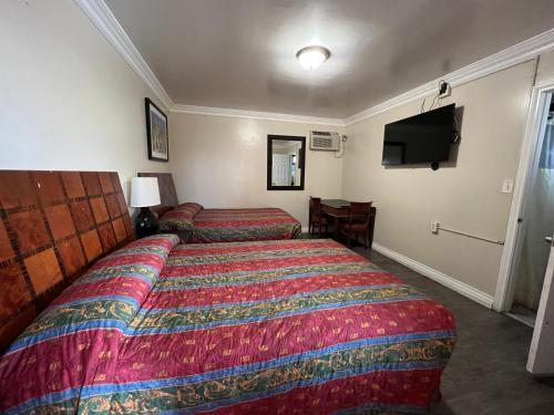 a hotel room with two beds and a flat screen tv at Flamingo Motel Oxnard in Oxnard