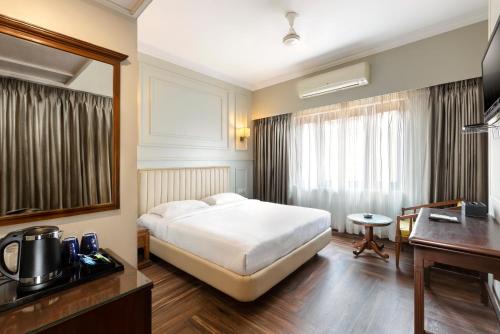 a hotel room with a bed and a desk at GRAND KALINGA HOTEL in Bangalore