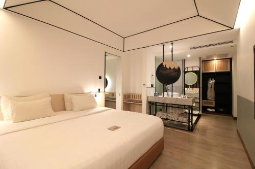 1 dormitorio con 1 cama blanca grande y espejo en GAIA Cosmo Hotel, en Yogyakarta