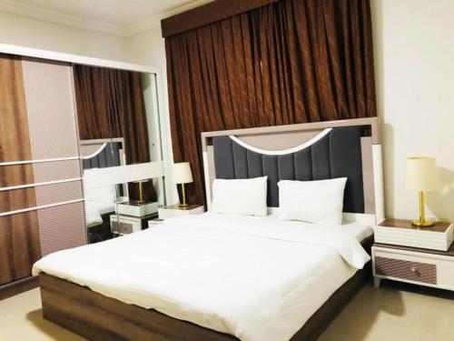 a bedroom with a large bed with white sheets and pillows at Majestic Hotel in Manama