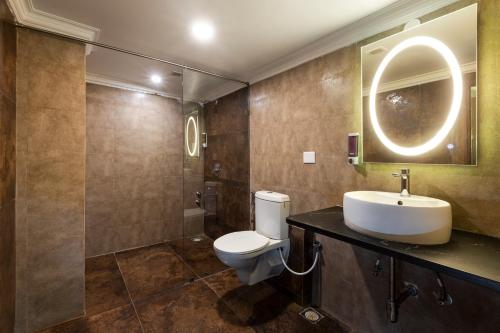 a bathroom with a toilet and a sink and a mirror at GRAND KALINGA HOTEL in Bangalore