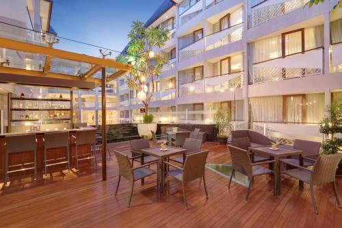 an outdoor patio with tables and chairs in front of a building at Episode Kuta Bali in Kuta